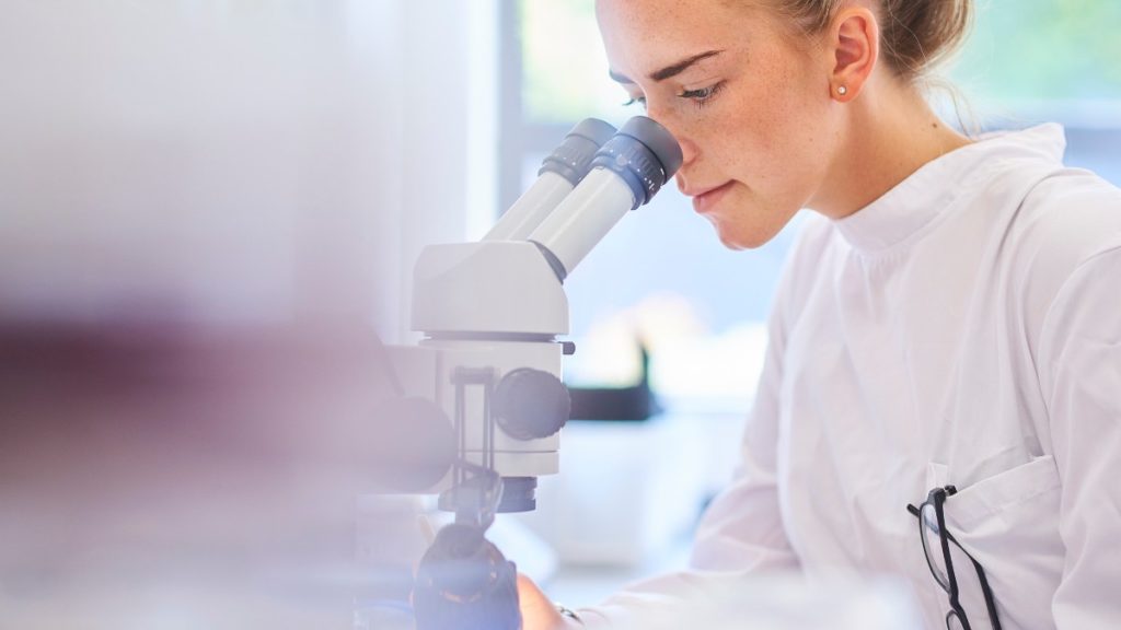 mulher olhando o microscópio:  faculdade de Zootecnia