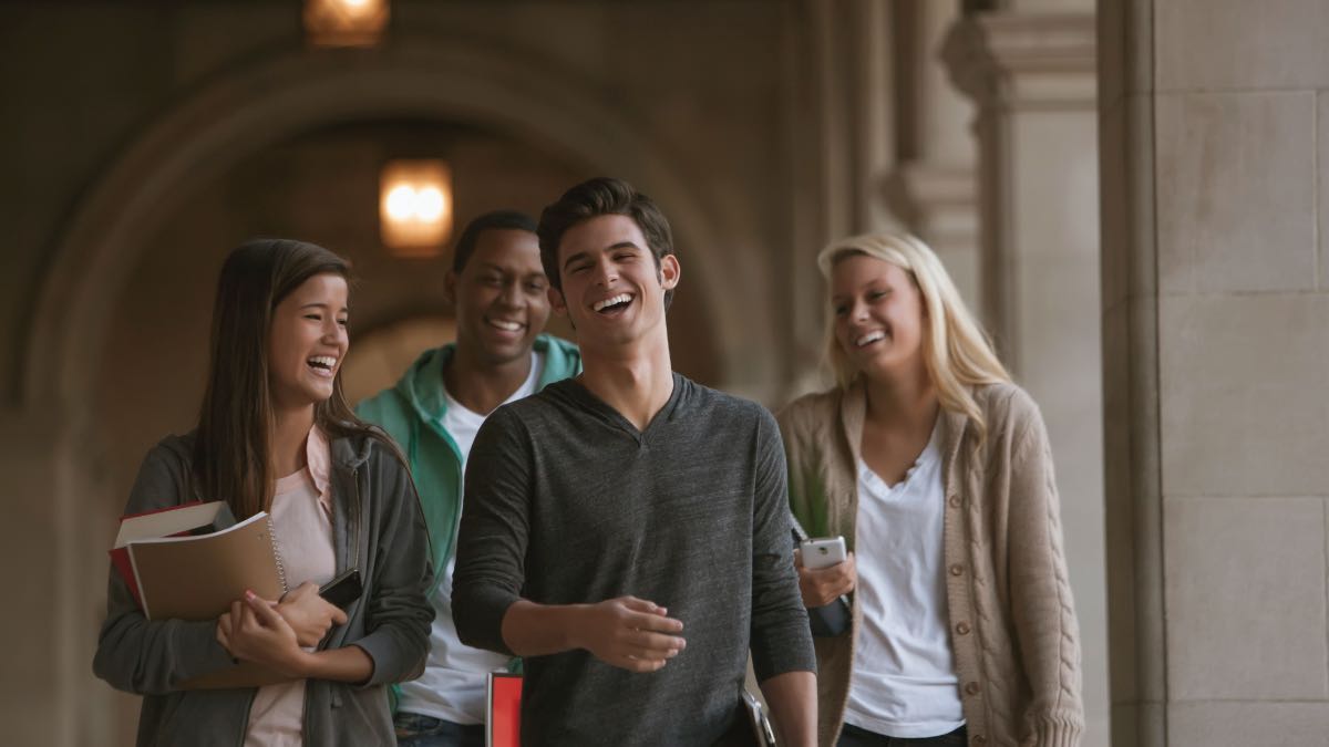 quatro estudante em pé dando risada: melhores faculdades de psicologia