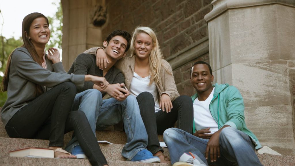 quatro estudantes sentados no degrau sorrindo: melhores faculdades de psicologia